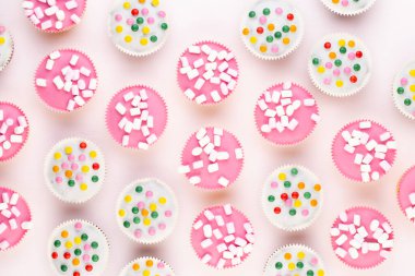 Beyaz arka planda çok renkli, güzel dekore edilmiş muffinler..