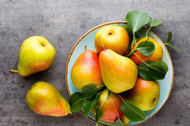 Tabağında yapraklar olan taze bir armut. Gri taş masa.