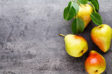 Tabağında yapraklar olan taze bir armut. Gri taş masa.