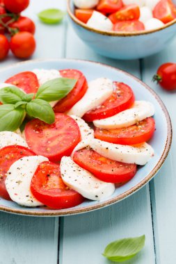 Domates, mozzarella peyniri, fesleğen ve baharatlar gri tahtada. İtalyan geleneksel Caprese salata malzemeleri. Akdeniz yemekleri.