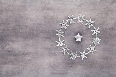 Noel kompozisyonu. Beyaz kar taneleri gri arka plandaki çelenkleri süslüyor. Noel, kış, yeni yıl konsepti. Düz konum, üst görünüm, kopyala.