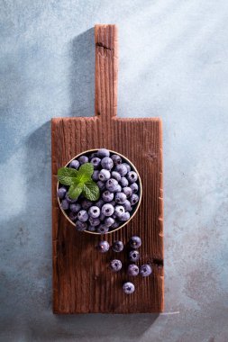 Köy tahtasında bir kase taze yaban mersini. Sağlıklı yaşam tarzı için organik yiyecek yaban mersini ve nane yaprağı..