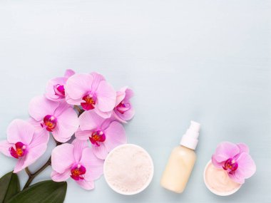 Spa aromaterapi arka planı, basit orkide çiçekleriyle süslenmiş çeşitli güzellik ürünleri..