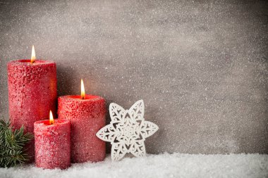 Gri arka planda üç kırmızı mum, Noel süsü. Havaya gir..
