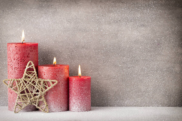Red burning candle on a snow background. Interior items.