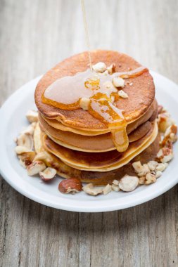 Ahşap arka planda ballı ev yapımı krep yığını.