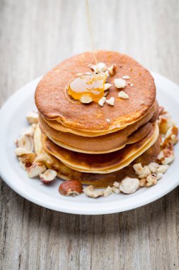 Ahşap arka planda ballı ev yapımı krep yığını.