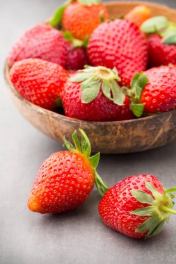 Gri arka planda bir kasede çilek.