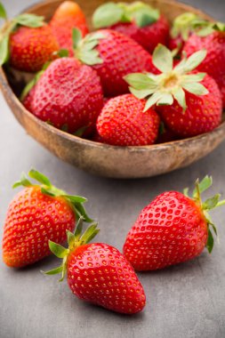 Gri arka planda bir kasede çilek.