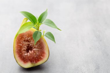 Gri bir masanın üzerinde tam bir incir ve bir incir dilimlenmiş.. 