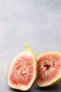 Gri bir masanın üzerinde tam bir incir ve bir incir dilimlenmiş.. 