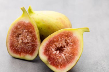 Gri bir masanın üzerinde tam bir incir ve bir incir dilimlenmiş.. 