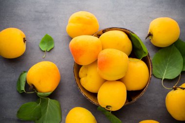 Ahşap arka planda yaprakları olan organik kayısılar..