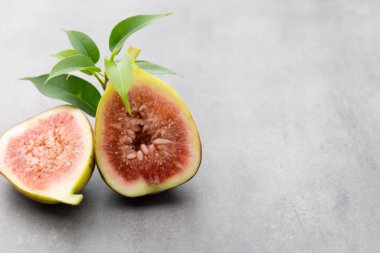 Gri bir masanın üzerinde tam bir incir ve bir incir dilimlenmiş.. 