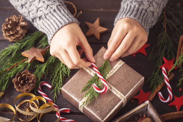 木のテーブルの上に置かれたクリスマスプレゼントを保持する女性 — ストック写真