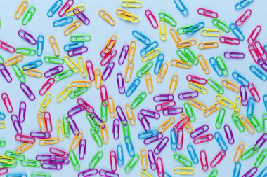 Mavi arkaplanda renkli ataçlar, boşluğu kopyala. Üst manzara, düz yatış. Okula dönmek, üniversite, eğitim konsepti. Renkli ataçların koleksiyonu. Soyut arkaplan.