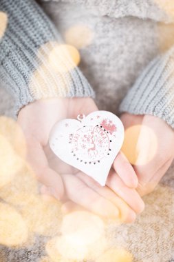 Kış Konsepti Genç Ellerin Noel süslerini tutması. Noel dekorasyonu fikri. Bir kadının elinde Noel süsü, altın sarısı bir arka plan.