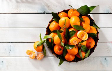 Tahta kutuda yaprakları olan taze mandalina portakalları..