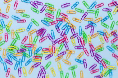 Mavi arkaplanda renkli ataçlar, boşluğu kopyala. Üst manzara, düz yatış. Okula dönmek, üniversite, eğitim konsepti. Renkli ataçların koleksiyonu. Soyut arkaplan.