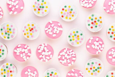 Beyaz arka planda çok renkli, güzel dekore edilmiş muffinler..