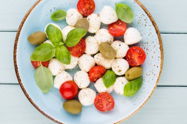 Kiraz domatesleri, mozzarella peyniri, fesleğen ve baharatlar gri tahta üzerinde. İtalyan geleneksel Caprese salata malzemeleri. Akdeniz yemekleri.