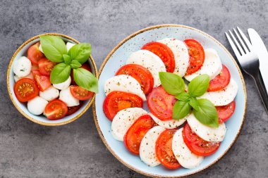 Domates, mozzarella peyniri, fesleğen ve baharatlar gri tahtada. İtalyan geleneksel Caprese salata malzemeleri. Akdeniz yemekleri.