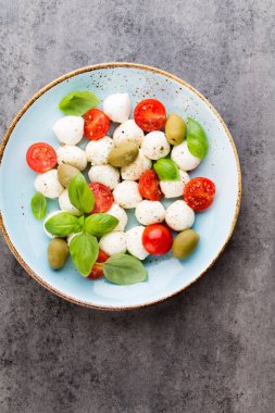 Kiraz domatesleri, mozzarella peyniri, fesleğen ve baharatlar gri tahta üzerinde. İtalyan geleneksel Caprese salata malzemeleri. Akdeniz yemekleri. 