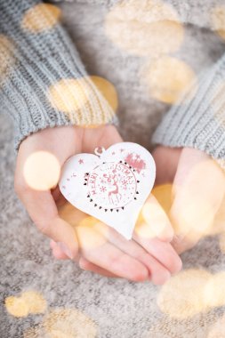Kış Konsepti Genç Ellerin Noel süslerini tutması. Noel dekorasyonu fikri. Bir kadının elinde Noel süsü, altın sarısı bir arka plan.