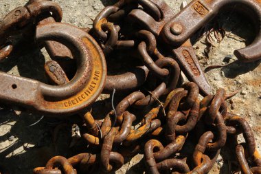 Eski paslı demir zincir bir kancayla sert bir yüzeyde yatıyor.