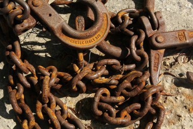 Eski paslı demir zincir bir kancayla sert bir yüzeyde yatıyor.