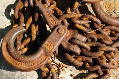 Eski paslı demir zincir bir kancayla sert bir yüzeyde yatıyor.