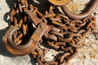 Eski paslı demir zincir bir kancayla sert bir yüzeyde yatıyor.