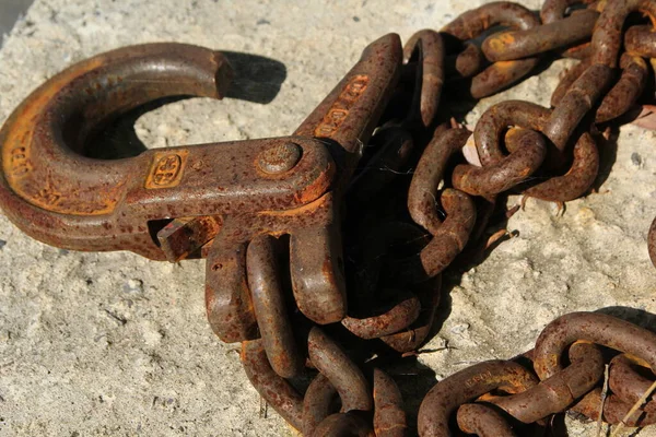 Old rusty iron chain with a hook lies on a rough surface — Stock Photo, Image