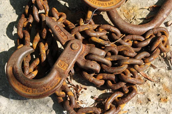 Eski paslı demir zincir bir kancayla sert bir yüzeyde yatıyor.