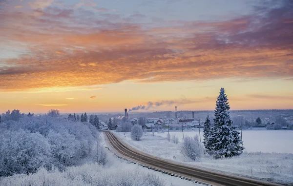 Winter sunset  road through snowy fields