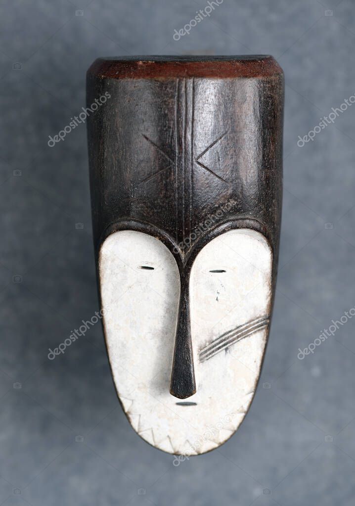 an ancient african wooden mask isolated over a gray background. Face mask of the ngil society, Gabon Africa