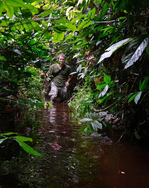 Photographer in the jungle goes through a bog.