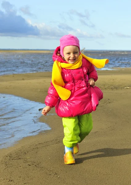 Маленькая девочка на песчаном осеннем пляже . — стоковое фото