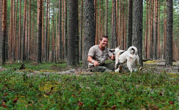 Man with the dog in the pine forest — Stock Photo, Image