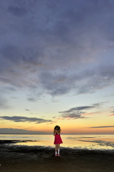 Pequena menina bonita jogando em uma praia de pôr do sol . — Fotografia de Stock