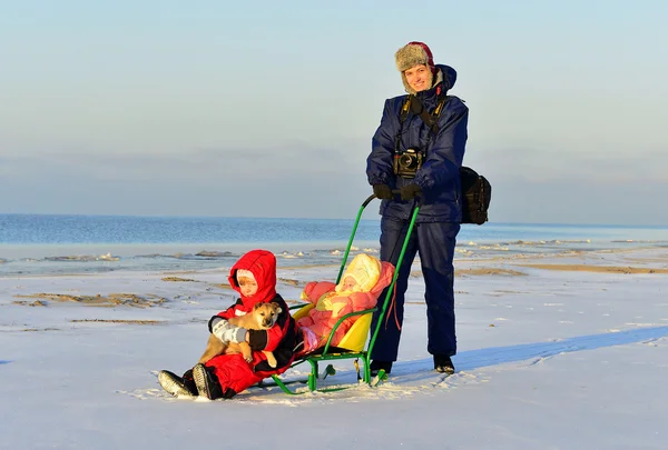 N soleggiata giornata invernale bella giovane madre passeggiate con due bambine sulla costa del lago Ladoga ghiacciato — Foto Stock