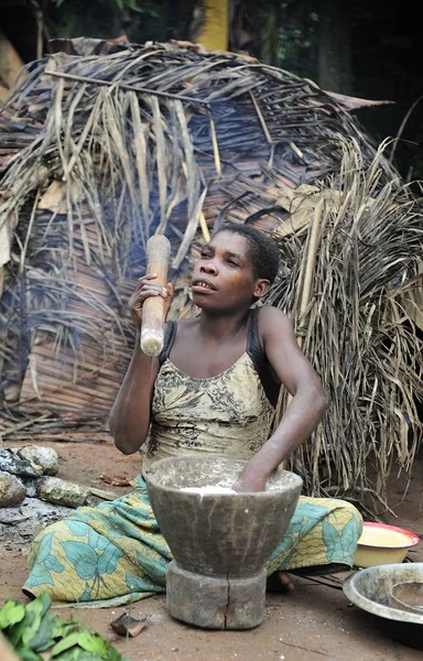 Baka femme cuisine de la nourriture, écrasant une farine dans un mortier — Photo