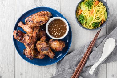 Teriyaki tavuk kanadı erişte ve sos ile servis edilir