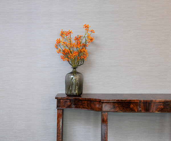 Sideboard in front of a grey wall with flower vase