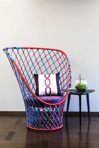 Плетеный стул перед простой стеной — стоковое фото