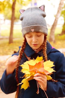 Küçük kız akçaağaç yapraklarına bakıyor..
