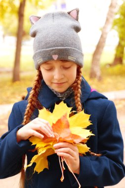 Küçük kız akçaağaç yapraklarına bakıyor..
