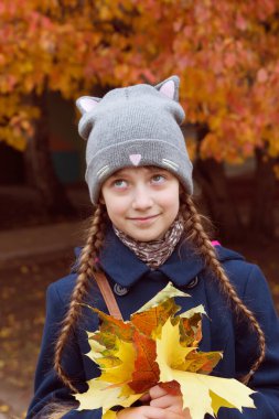 Küçük kız akçaağaç yapraklarını tut..