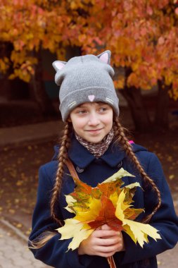 Küçük kız akçaağaç yapraklarını tut..