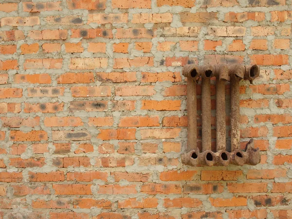 Verwoeste gietijzeren radiator voor huis op een bakstenen muur. — Stockfoto